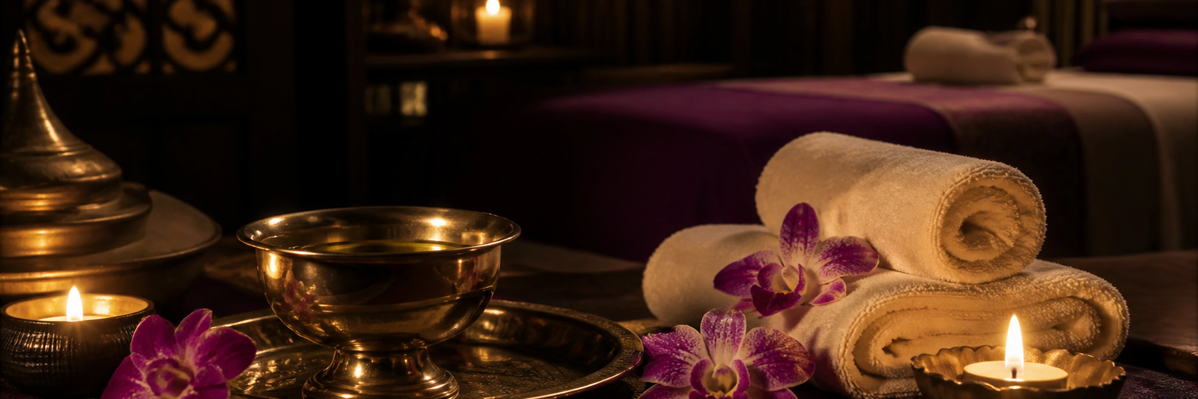 Warm massage oil, orchids and folded towels in a peaceful spa setting